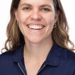 Headshot of a smiling woman with light brown hair wearing a navy Bushnell polo shirt against a white background