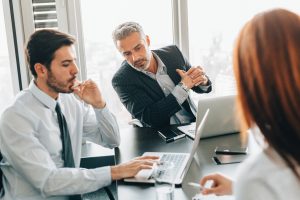 Business firm meeting with professionally dressed employees looking at a computer