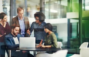 Colleagues in a group discuss a project in business office around computer
