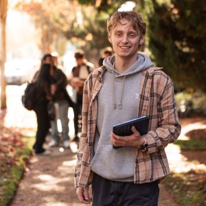 Interdisciplinary studies student holding tablet on crosswalk in the sun