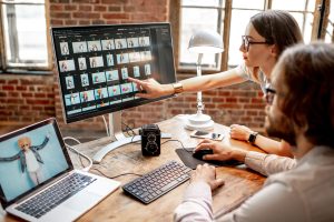 Digital media professionals reviewing photography and graphic design projects on a computer monitor
