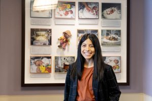 Student in a healthcare administration internship dressed professionally standing in front of a NICU display