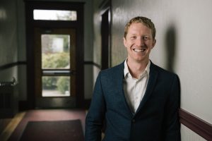 Professionally dressed graduate smiling in a hallway