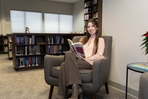 Student reads a book while sitting on a chair in a bookstore