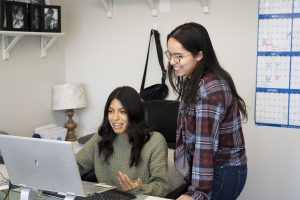 Communication students collaborating on computer-based work in an office environment